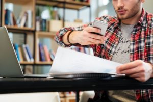 Person holding phone taking a picture of document held in other hand